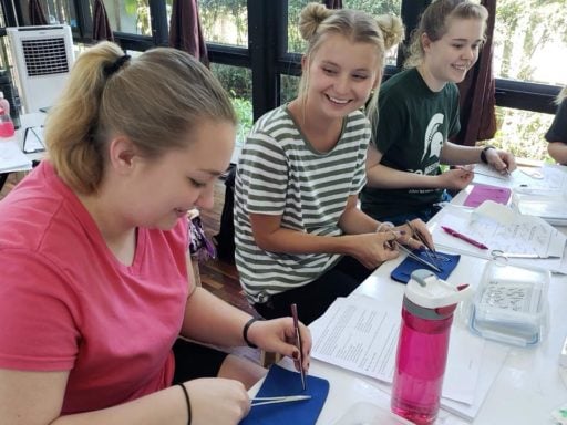 Young Loop Abroad students chatting while doing a suture practice