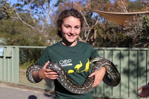 A smiling student holding a snake