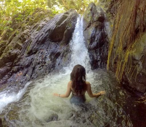 Young woman enjoying her time in a small gushing water from falls